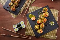 Deliciosas piezas de crujiente rollo de sushi california en pizarra - foto de stock