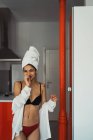 Rindo jovem mulher em lingerie e toalha na cabeça de pé na cozinha — Fotografia de Stock