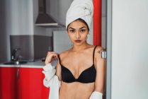 Sensual jovem mulher em lingerie e toalha na cabeça de pé na cozinha — Fotografia de Stock