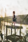 Sinnliche junge Frau steht auf Holzsteg am See — Stockfoto