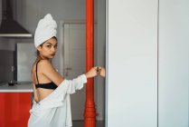 Sensual jovem mulher em lingerie e toalha na cabeça de pé na cozinha — Fotografia de Stock
