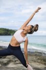 Junge, fitte Frau dehnt sich beim Yoga am Meer — Stockfoto
