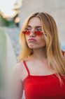 Jeune femme en débardeur et lunettes de soleil grimacant à l'extérieur — Photo de stock