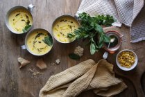 Maiscremesuppe mit Kokos und Pesto in Schalen auf Holztisch mit Zutaten — Stockfoto