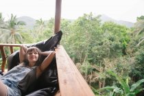 Jeune femme couchée sur la terrasse dans la forêt tropicale et regardant loin — Photo de stock