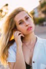 Blond young standing outdoors in sunlight and looking at camera — Stock Photo
