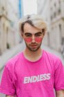 Ritratto di un uomo elegante in occhiali da sole rosa a forma di cuore in piedi sulla strada — Foto stock