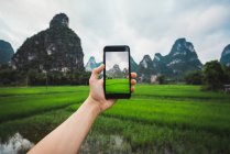 Mano humana tomando fotos de campos de arroz y montañas únicas, Guangxi, China - foto de stock