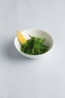 Японский салат из водорослей с лимонным клином в белой миске — стоковое фото