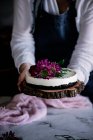 Женщина на полях держит торт с цветами — стоковое фото