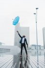 Етнічні бізнесмен лову парасолька стоячи мокра бруківка в місті — стокове фото