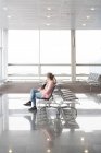 Туристка сидит на скамейке в терминале аэропорта — стоковое фото