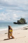 Jeune femme détendue en bikini posant sur une plage de sable — Photo de stock
