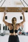 Vue arrière de la femme forte en vêtements de sport debout près de la planche en bois dans la salle de gym avec les mains en l'air — Photo de stock