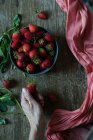 Prendre à la main de délicieuses fraises du bol — Photo de stock