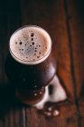 Ставлене пиво в склянці на темному дерев'яному столі — стокове фото