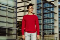 Attractive  young man standing in front of building and looking away — Stock Photo