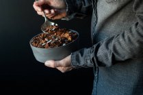 Male hands holding bowl of crunchy quinoa granola on dark background — Stock Photo