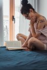 Sinnliche brünette Frau mit Buch chillen auf dem Bett — Stockfoto