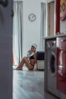 Jeune femme sensuelle en lingerie et serviette sur la tête assis sur le sol à la maison — Photo de stock