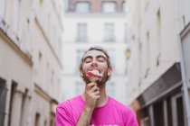 Stylischer Mann im rosafarbenen T-Shirt isst Eis auf der Straße — Stockfoto
