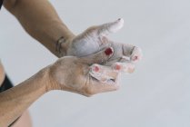 Mains féminines avec tatouage écartant la craie sur les mains sur fond blanc — Photo de stock