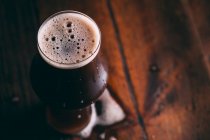 Birra robusta in vetro su tavolo di legno scuro — Foto stock