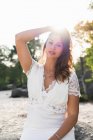 Charmante Brünette trägt elegantes Brautkleid mit Halskette und blickt in die Kamera im Freien — Stockfoto