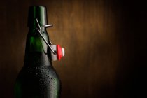 Botella de cerveza fría abierta sobre fondo oscuro - foto de stock