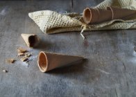 Coni di cialde vuoti per gelato su tavolo di legno grigio — Foto stock