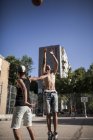 Afro jóvenes hermanos jugando baloncesto en la cancha de barrio - foto de stock