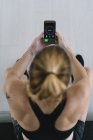 Sportlerin sitzt und nutzt Fitness-App auf Smartphone — Stockfoto