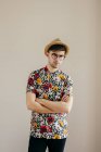 Stilvoller junger Mann posiert mit verschränkten Armen vor grauer Wand — Stockfoto