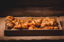 Mélange de croissants dorés dans un plateau en bois — Photo de stock