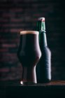 Ставлене пиво в склі та пляшці на дерев'яному столі на темному фоні — стокове фото