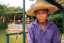 Smiling aged Asian fisherman in straw hat looking at camera outdoors — Stock Photo