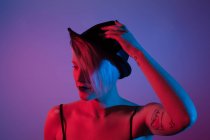 Привлекательная женщина с шляпной съемкой в студии с синим и красным огнями — стоковое фото