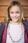 Retrato de menina loira sorridente com olhos azuis de pé fundo de madeira — Fotografia de Stock