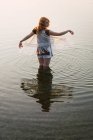 Woman standing in clear water of lake and gesturing with hands — Stock Photo