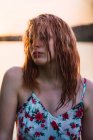 Чуттєва жінка в одязі з мокрим волоссям на березі озера на заході сонця — стокове фото