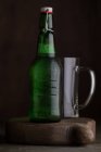 Botella de cerveza y vidrio sobre tabla de madera sobre fondo oscuro - foto de stock