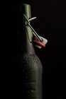 Close-up of opened cold beer bottle on black background — Stock Photo