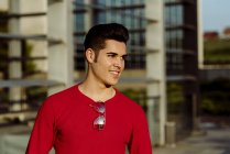 Portrait of young man standing in front of building and looking away — Stock Photo