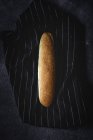Pan pan recién horneado en tela oscura rayada - foto de stock