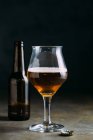 Copo de cerveja no fundo escuro com garrafa — Fotografia de Stock