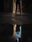 Ernte unkenntliche Balletttänzerin steht auf Zehenspitzen und reflektiert in der Pfütze auf der Straße. — Stockfoto