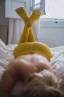 Mulher em collants levantando pernas em meias amarelas enquanto deitado na cama — Fotografia de Stock