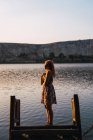 Frau im Sommerkleid steht auf versunkener Seebrücke im Sonnenlicht — Stockfoto