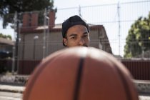 Jovem afro menino segurando basquete na quadra ao ar livre — Fotografia de Stock