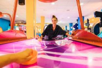 Woman playing on air hockey table and looking at camera — Stock Photo